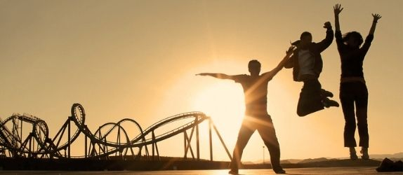 silhouette of people leaping for joy in front of a roller coaster