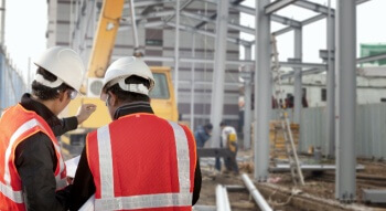 two construction workers looking at plans on a work site