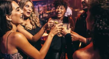 A group of friends toasting drinks at a bar