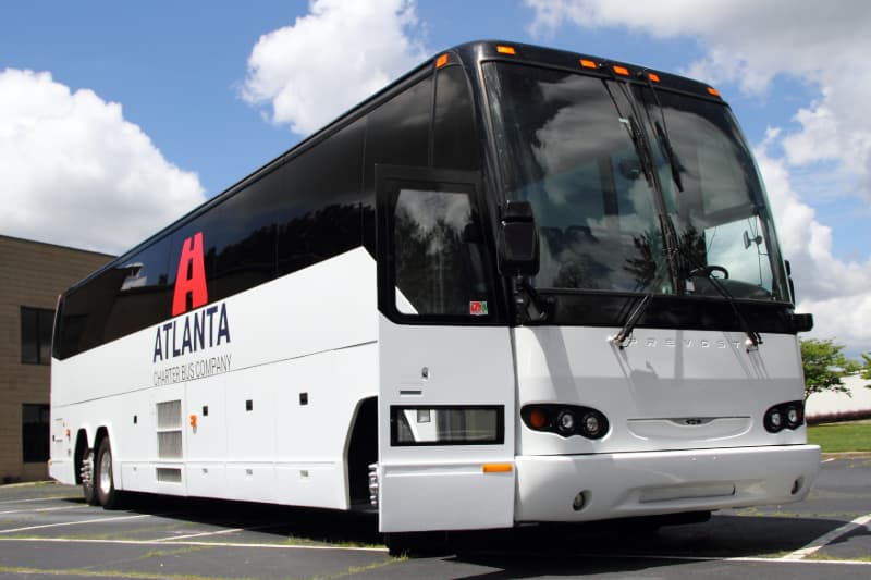 A branded Atlanta Charter Bus Company charter bus parks in an empty lot